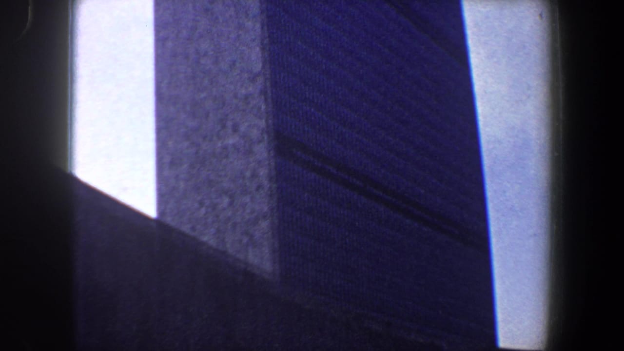 Tall textured building wall beside a dark central vertical obstruction.