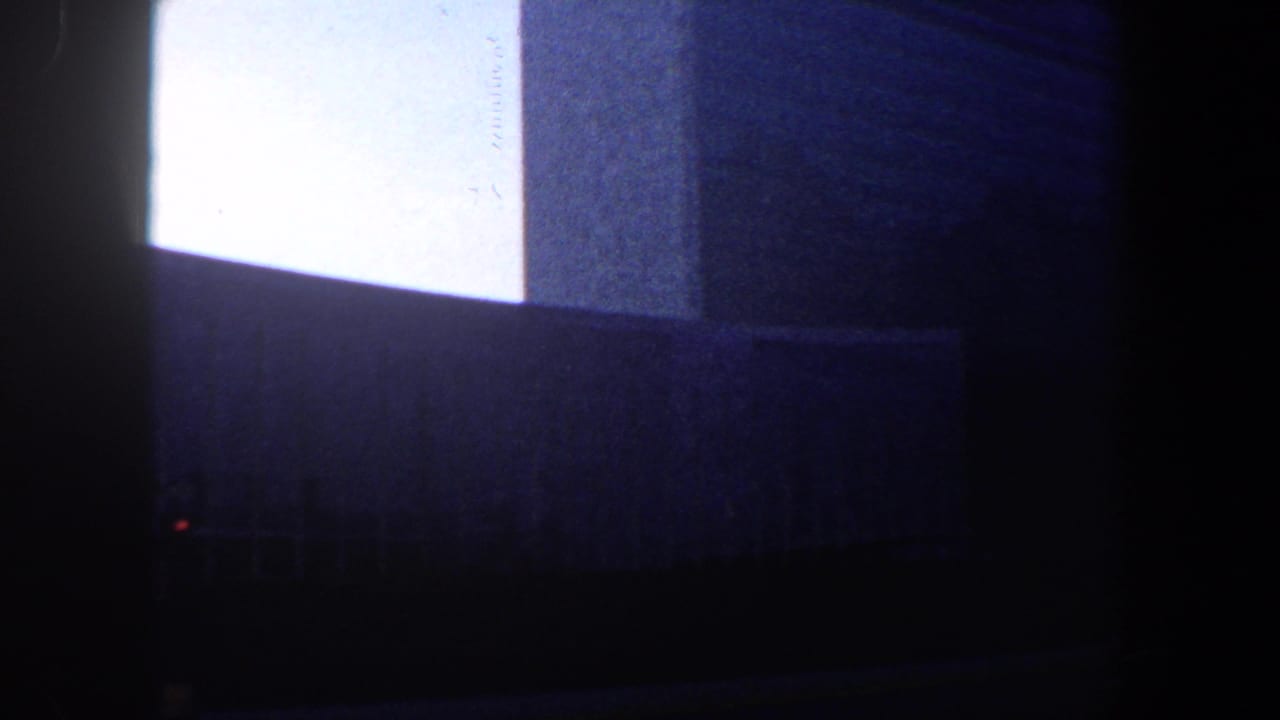 Low-angle view of a tall building facade with bright sky and dark street foreground.