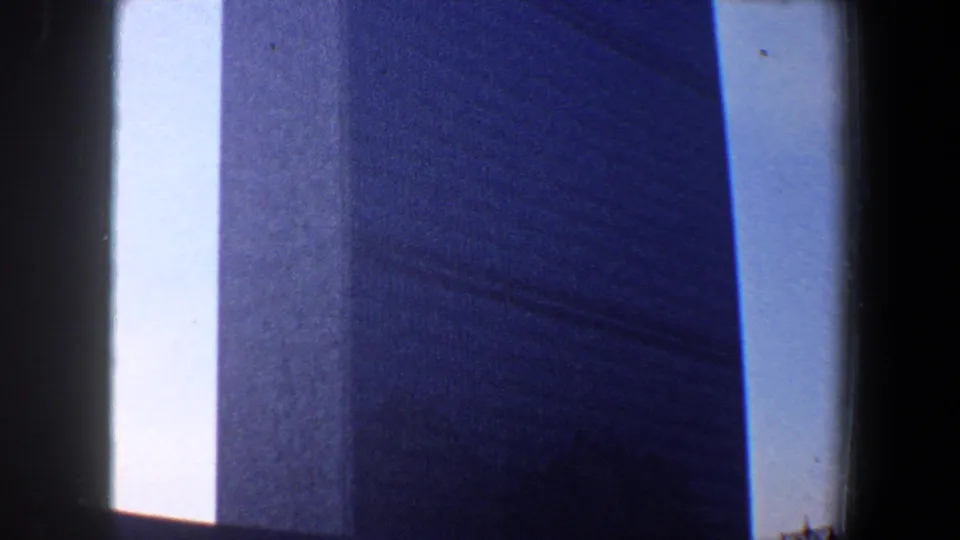 1960 New York City 8mm frame focused tightly on a tall building wall rising beside a bright strip of sky.