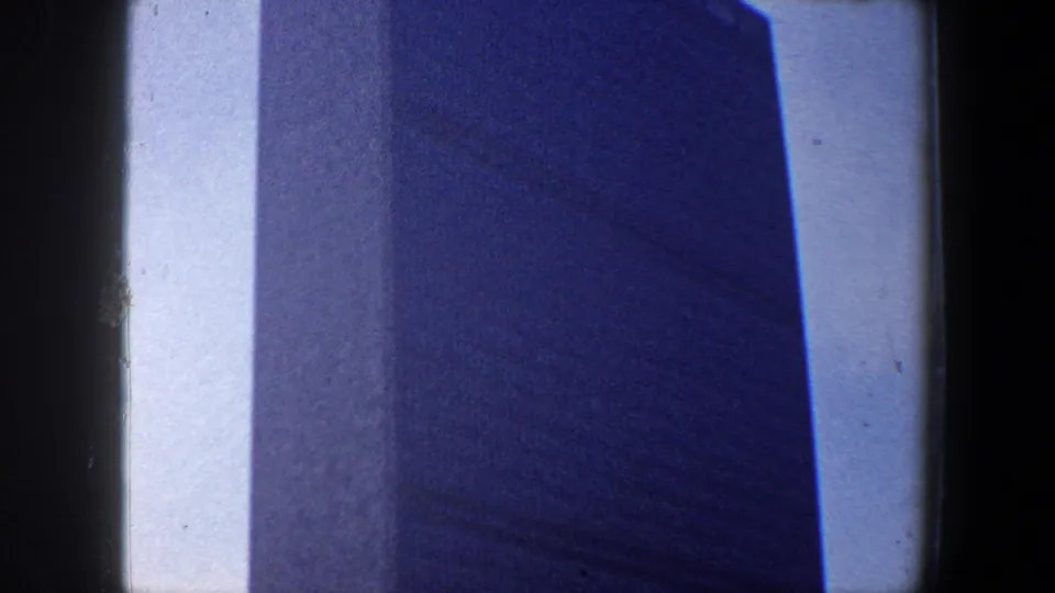 Final 1960 New York City low-angle frame with the building facade dominating the view and sky reduced to a slim vertical strip.