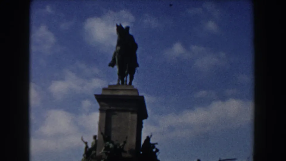 1959 Rome frame with the rider and horse silhouetted above a rectangular stone pedestal under a bright, clouded sky.