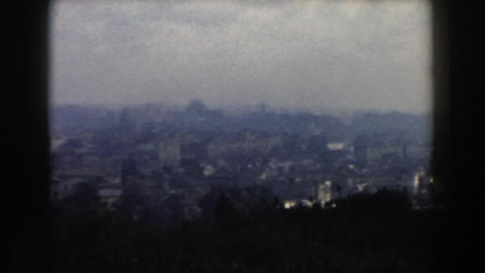 Hazy 1959 Rome panorama with dark foreground forms and indistinct buildings across the distance.