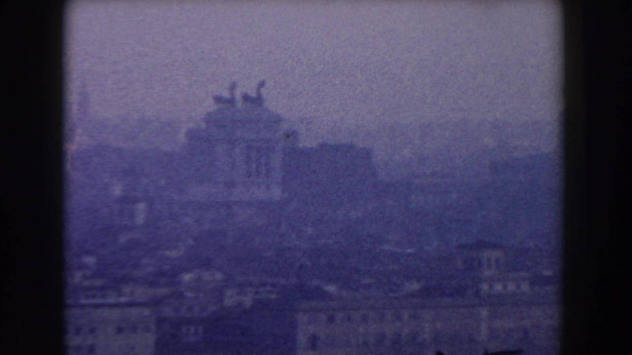 Hazy Rome skyline with distant classical building silhouettes and dark film-frame borders.