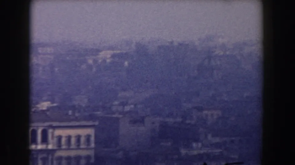 The 1959 home-movie frame looks across Rome from above, with soft buildings fading into haze.