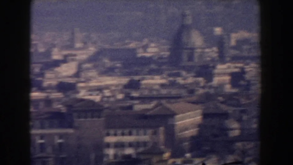 Elevated 1959 Rome view showing domed architecture and dense rooftops beneath a hazy blue-tinted sky.