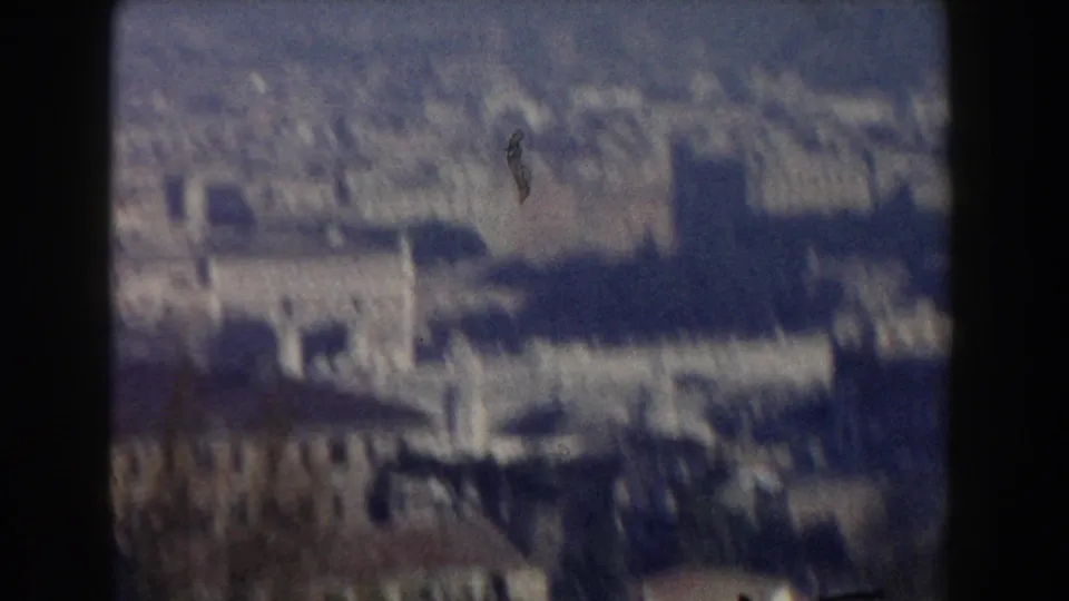 1959 8mm home-movie frame showing a blurred elevated view across Rome buildings, treetops and hazy sky.