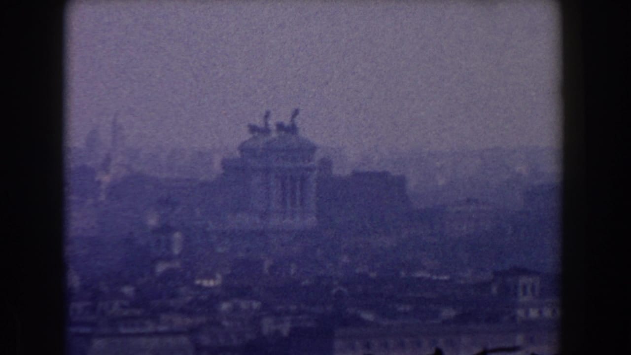 Hazy Rome skyline with a large monument and statues seen through a soft blue 8mm frame.