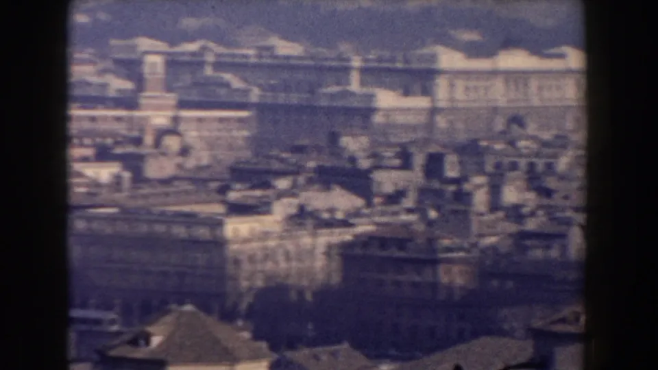 1959 Rome elevated view with broad classical buildings, dense rooftops, distant hills, and faded 8mm color texture.