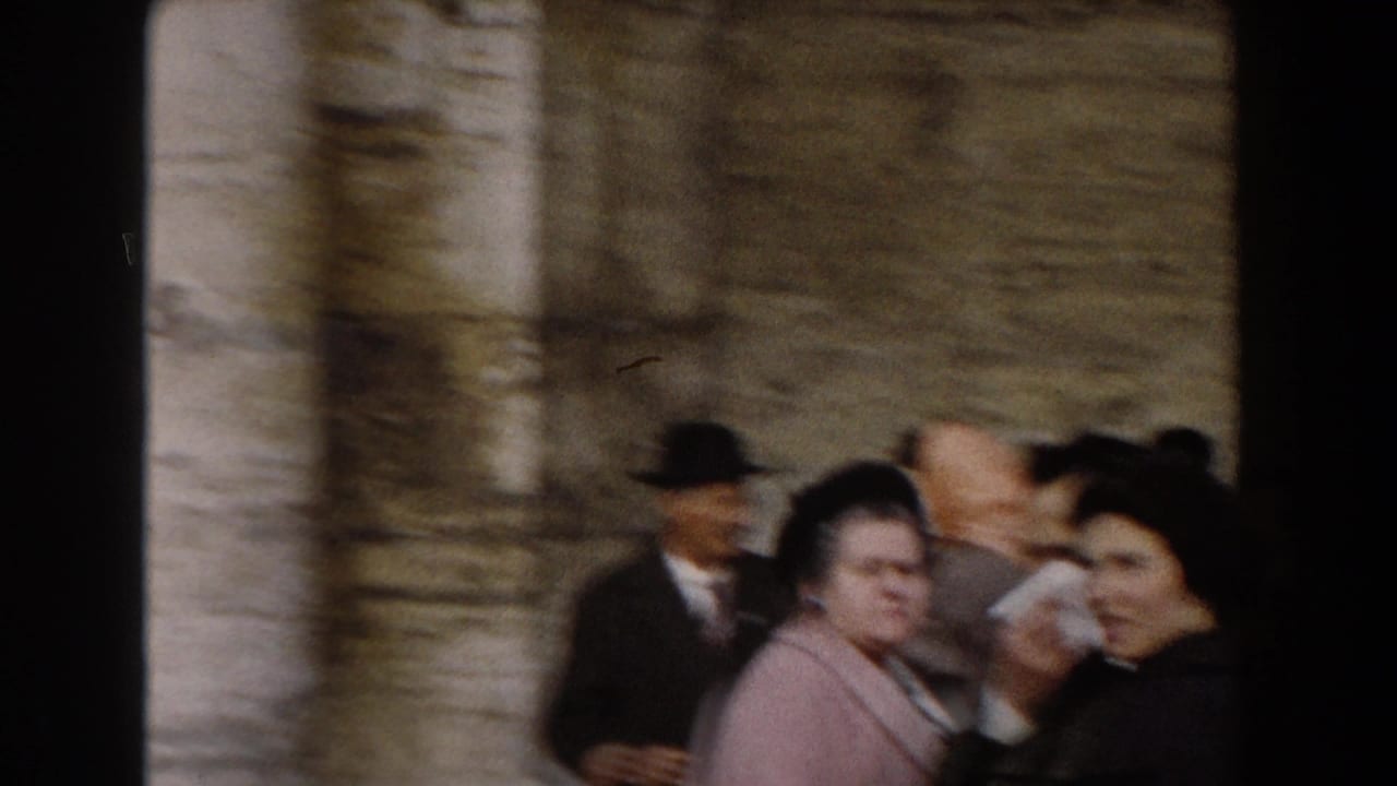 Crowd of adults outside a stone church, with women in coats and men in hats near large columns.