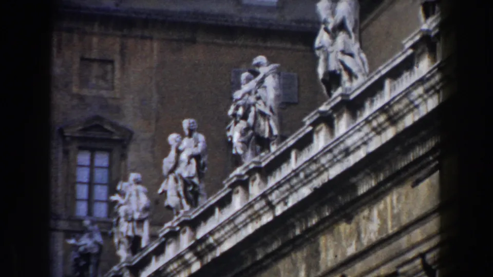 1959 Rome exterior view of pale rooftop statues above a dark stone facade and window.