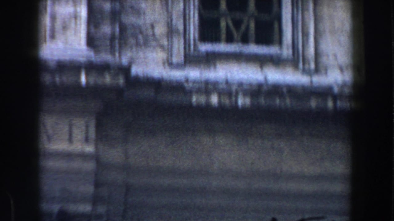 1959 Rome 8mm frame showing a weathered stone building facade with a window, carved ornament, and heavy exposure falloff.