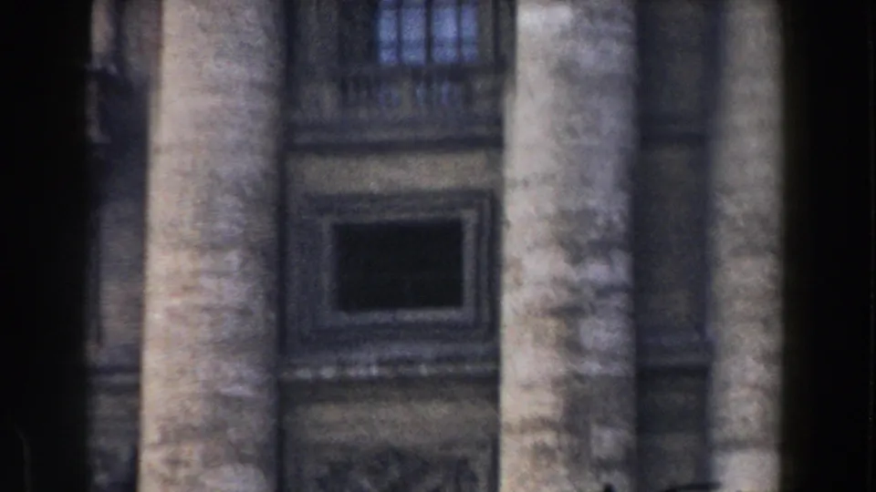 Rome 1959 8mm frame with tall weathered columns, a dark rectangular window, and carved stone panels behind them.