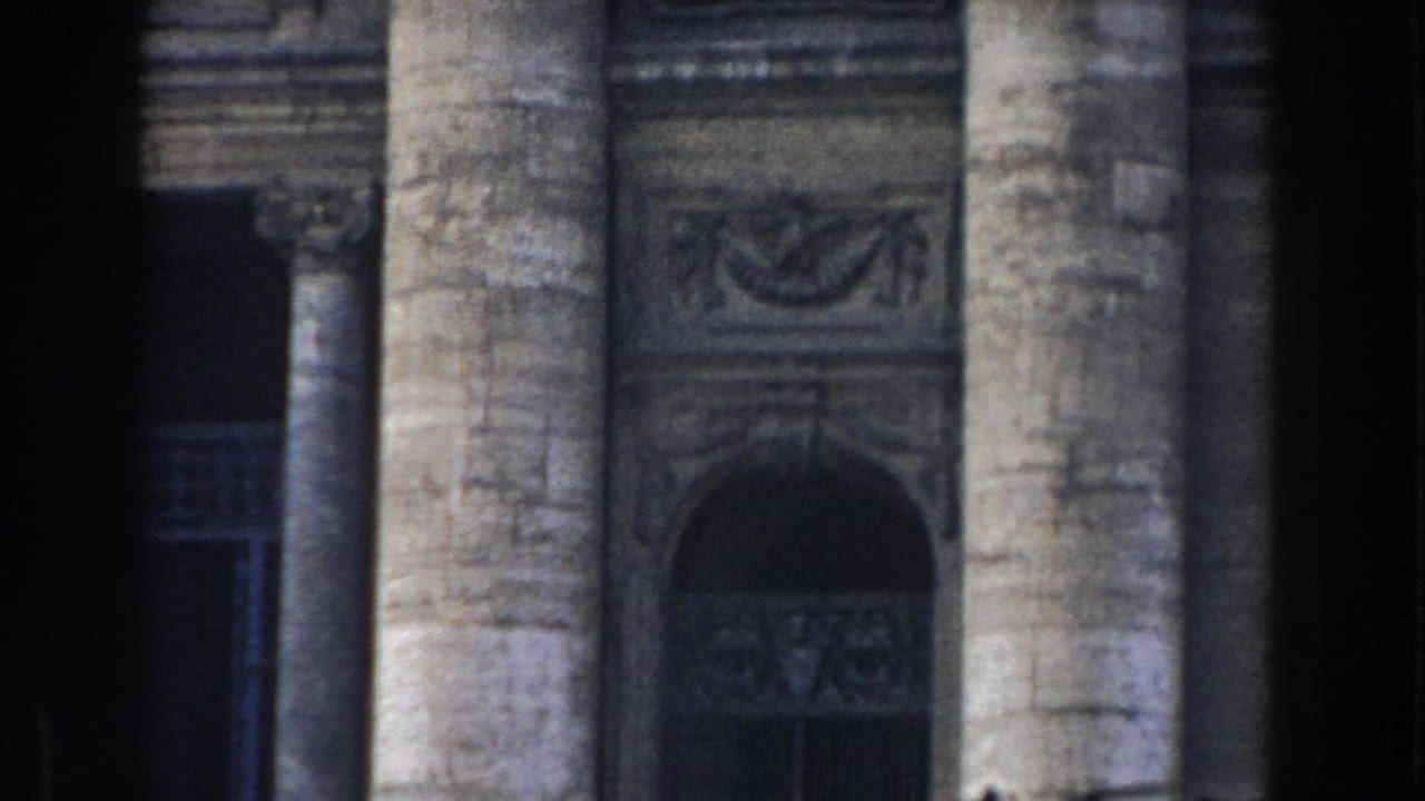 1959 Rome home-movie frame showing tall stone columns, carved architectural details, and a shadowed arched entrance.
