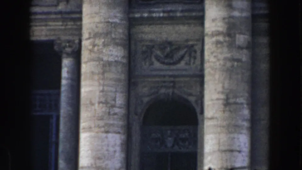 1959 Rome home-movie frame showing tall stone columns, carved architectural details, and a shadowed arched entrance.