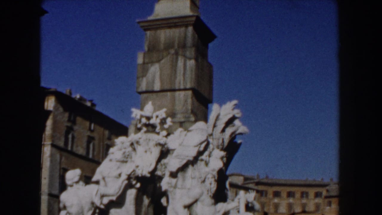 White sculptural figures and part of a tall column against a blue sky.