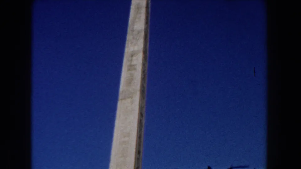 1959 Rome 8mm frame showing the column shaft with pale sculptural details near the lower edge and clear blue sky behind it.