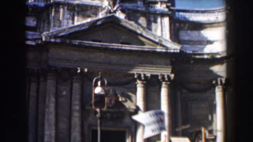 1959 Rome frame showing a columned classical facade with a triangular pediment and visible Red Cross banner near the entrance.