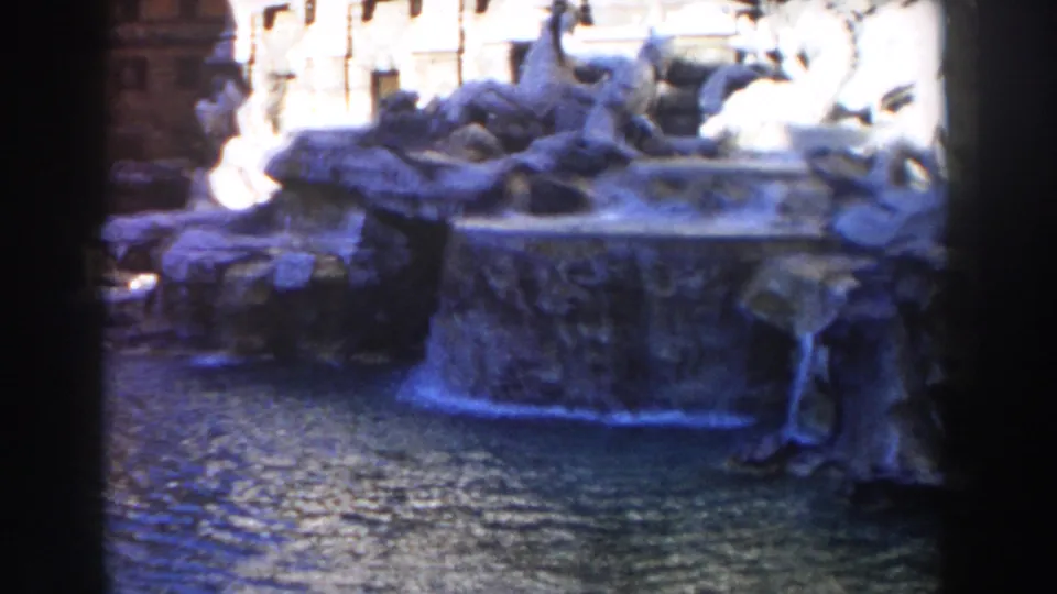 1959 home-movie frame of the Trevi Fountain with bright stone sculptures, falling water, and a rippling pool.