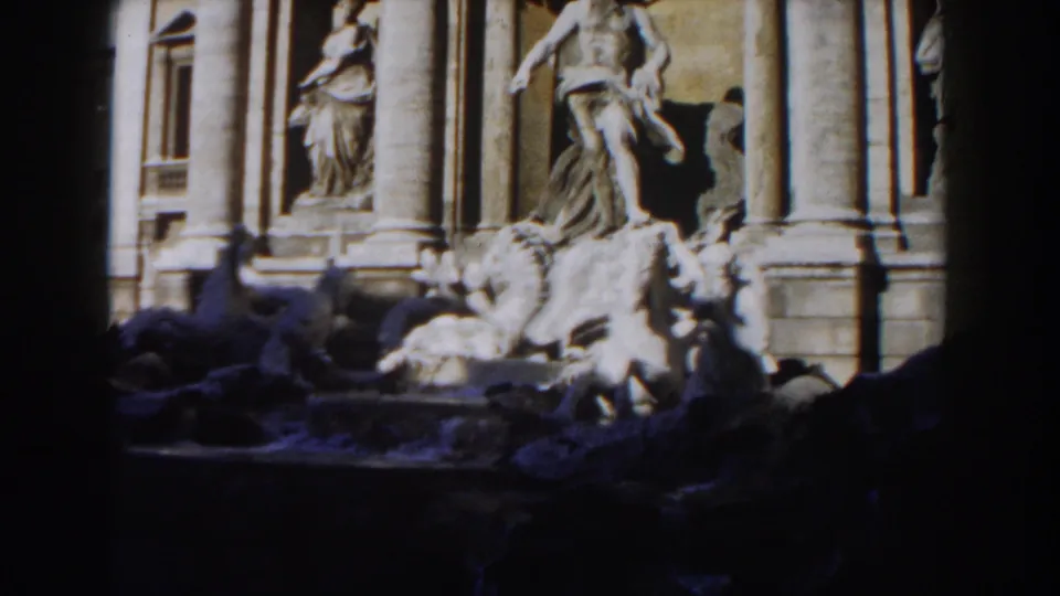 Rome's Trevi Fountain appears in bright sun and heavy shade, showing columns, statues, and the upper stone basin.