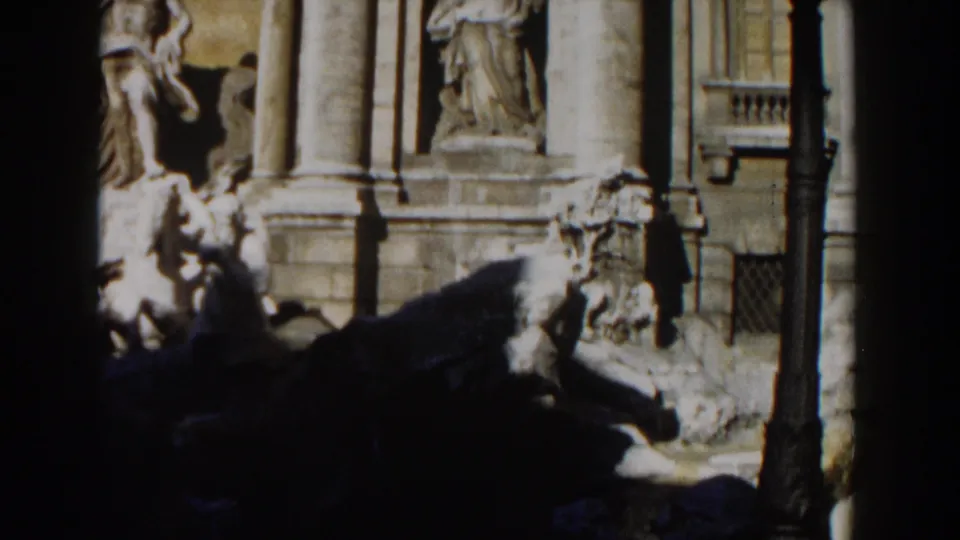 1959 Rome 8mm frame showing Trevi Fountain stone figures and columns partly obscured by a dark foreground edge.