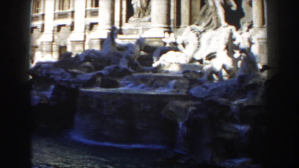 1959 Rome 8mm frame showing the Trevi Fountain basin, sculptural group, and blue-tinted water under strong sunlight.