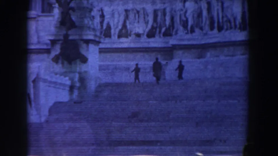 1959 Rome travel frame showing three small figures on broad stone steps, with sculpted monument detail and a statue base at left.