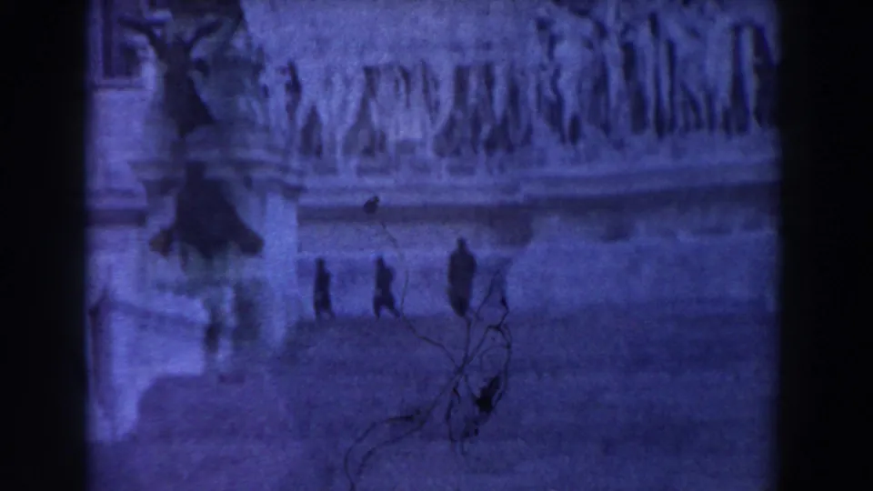 Blue-tinted 1959 Rome home-movie frame with small walkers on stone steps, sculpted reliefs above, and dark branches in the foreground.