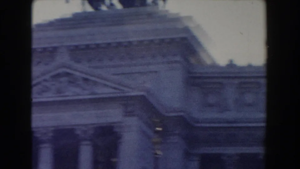 1959 Rome frame showing an upper classical facade with columns, a pediment, and silhouetted horse statues on the roofline.
