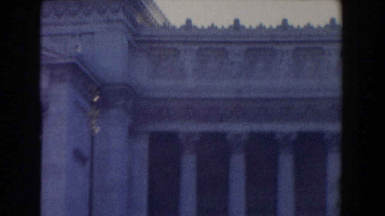 Classical stone building facade with tall columns and ornate roofline.