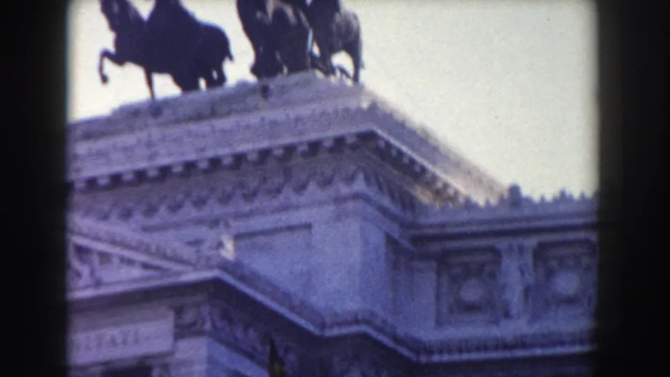 1959 Rome frame showing a rooftop equestrian or chariot sculpture on a grand stone monument against pale sky.