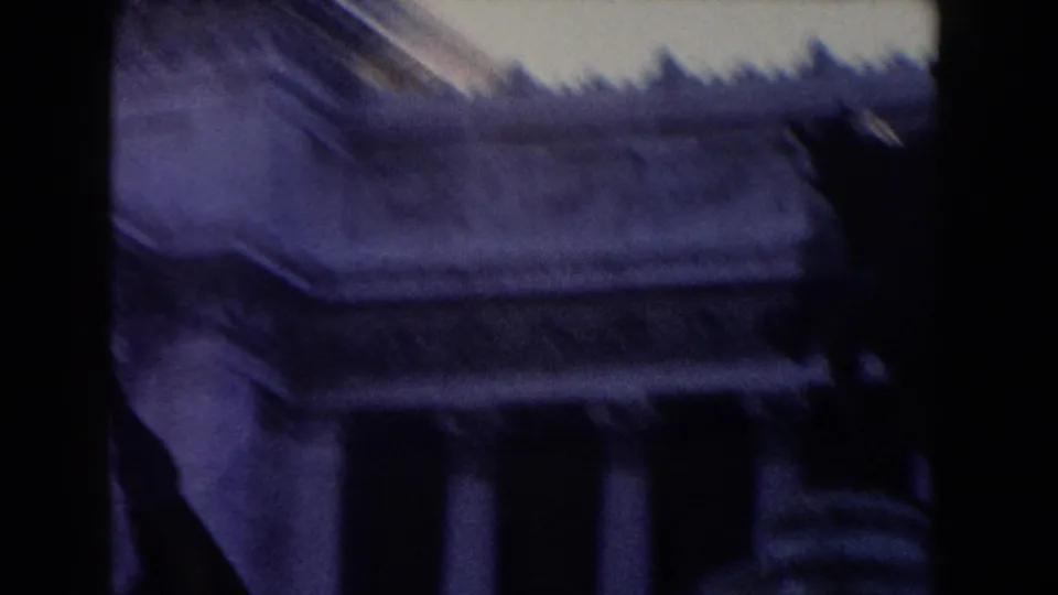 1959 Rome 8mm view of a monumental roofline and columns, with handheld framing and blue-purple film color shift.