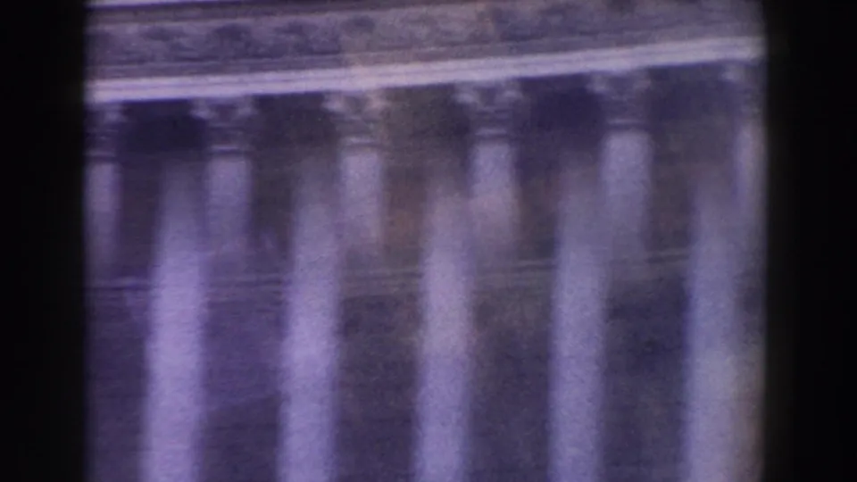 1959 Rome frame with a blurred row of columns and upper stone molding, colored by aged 8mm stock.