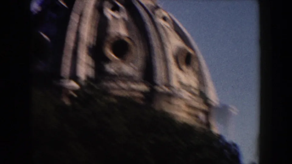1959 Rome frame with a domed classical structure partly obscured by foliage, filmed in soft handheld 8mm color.
