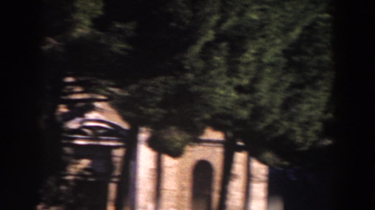 Tree-shadowed Rome building facade seen through a dark vertical frame.