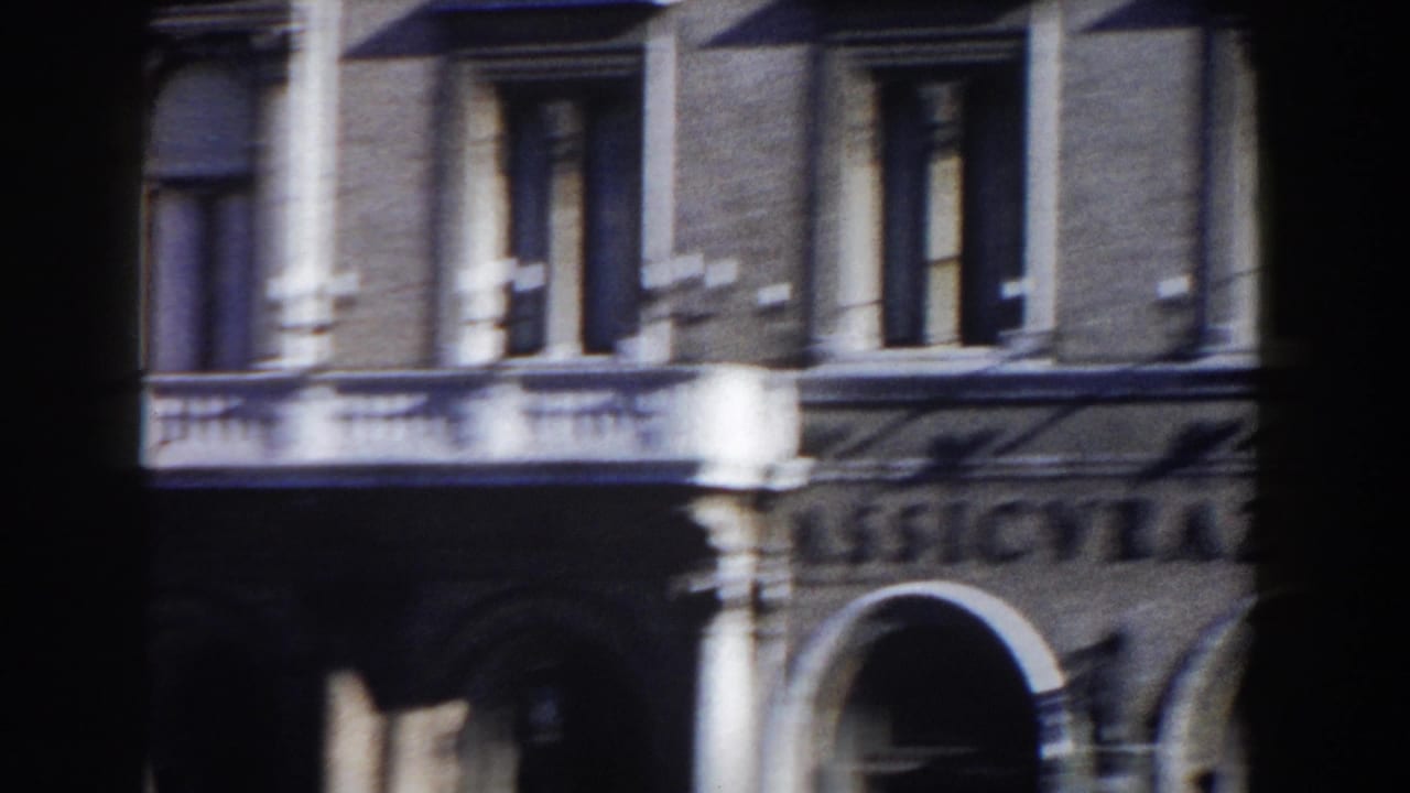 Ornate building facade with columns, arched openings, and shuttered windows.