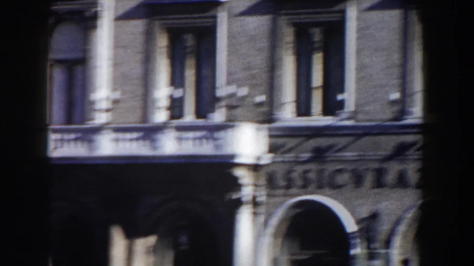 1959 Rome 8mm frame showing a historic facade with columns, balconies, arched openings, and shuttered upper windows.