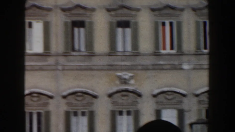 1959 Rome 8mm frame showing a multi-story facade with repeated shuttered windows, decorative lintels, and a dark edge at the side.