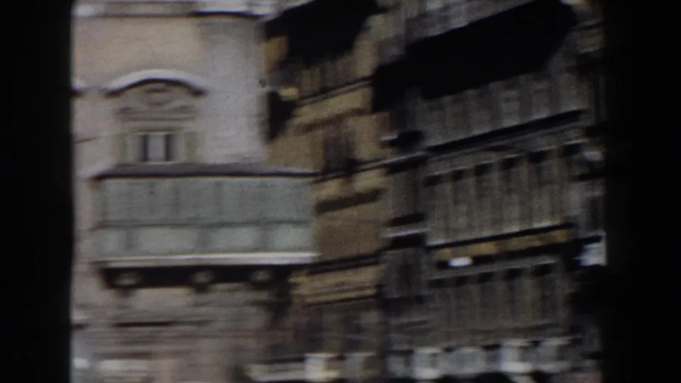 1959 Rome 8mm view of adjoining facades and a balcony, partly obscured by dark vertical and circular foreground shapes.