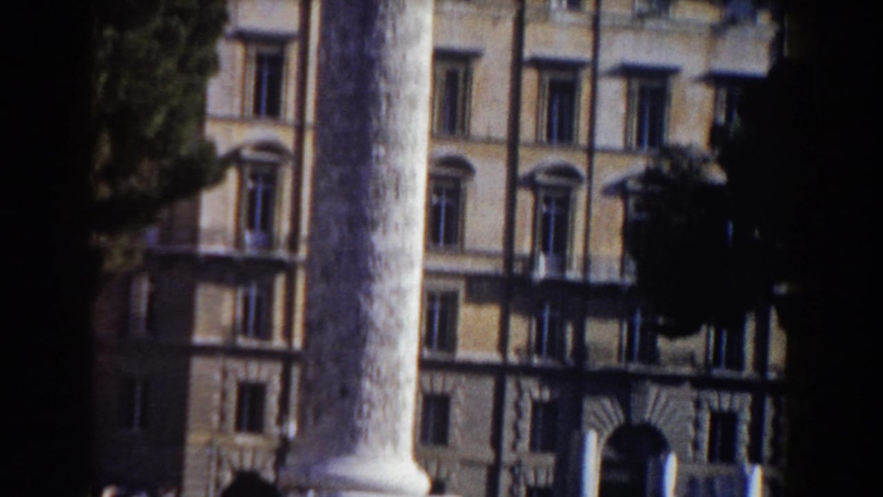 1959 Rome home-movie frame showing a large column, arched windows, and a historic-looking facade in bright daylight.