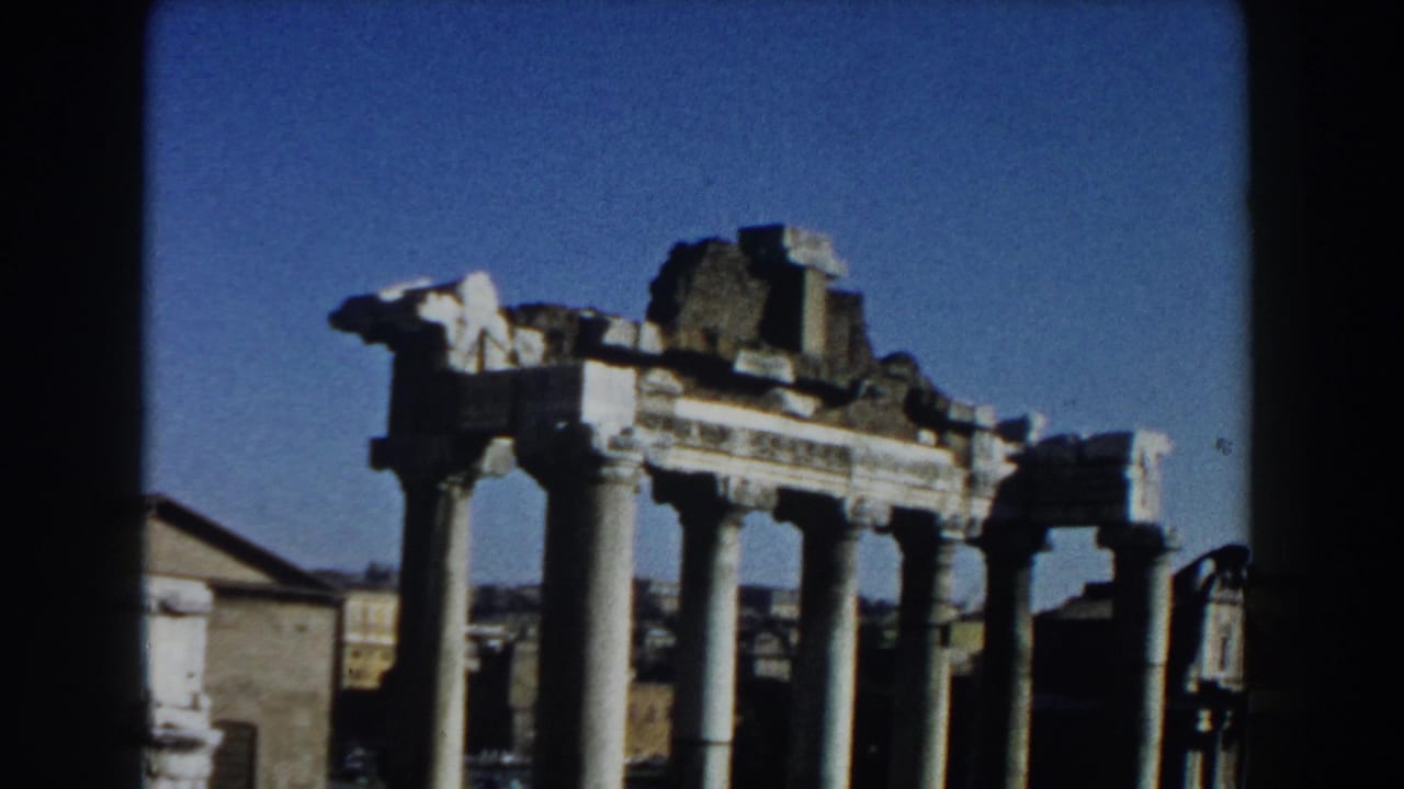 1959 Rome home-movie frame showing tall pale columns and ruined stone structures against a clear blue sky.