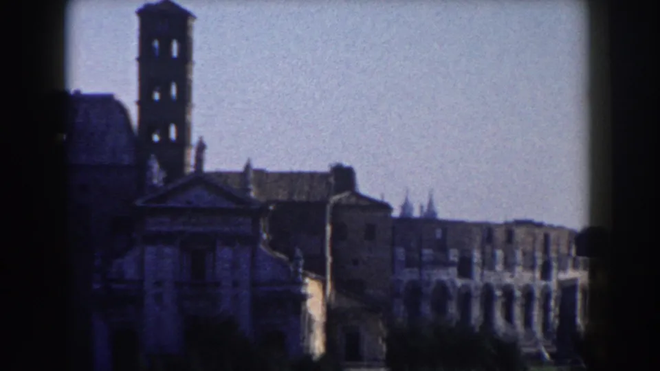 1959 Rome frame showing a towered historic building and the Colosseum's arched exterior in the background.