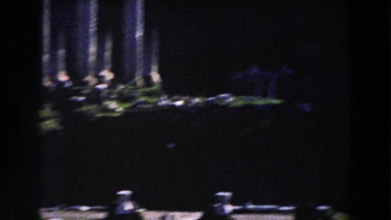 1959 Rome home-movie frame showing tall stone columns and shadowed archaeological remains with a heavy film vignette.