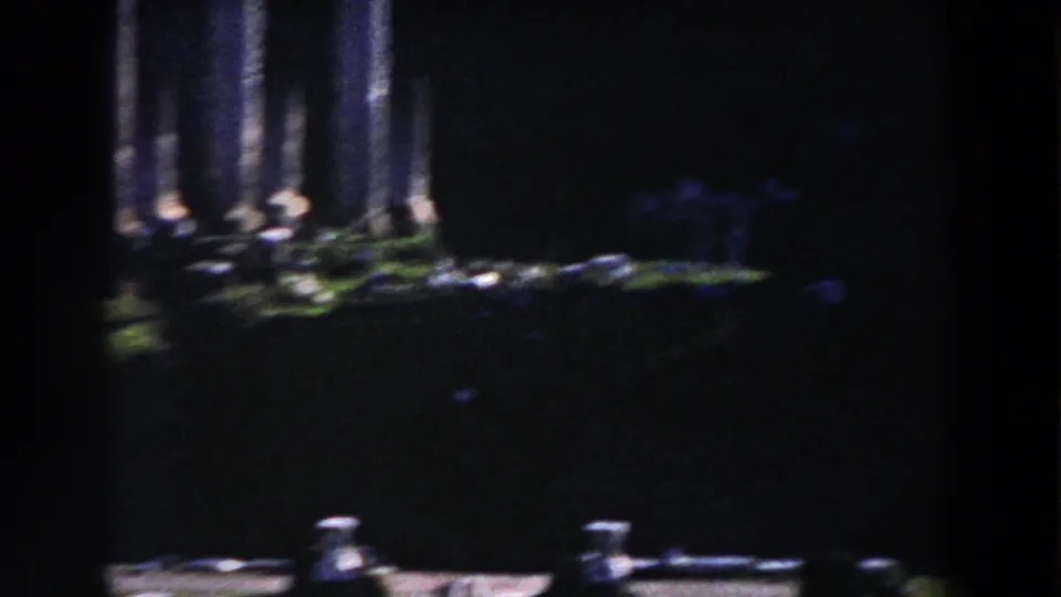 1959 Rome home-movie frame showing tall stone columns and shadowed archaeological remains with a heavy film vignette.