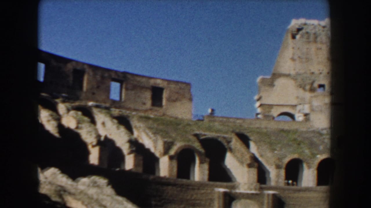 Upper Colosseum arches and broken stonework seen through dark film-frame edges.