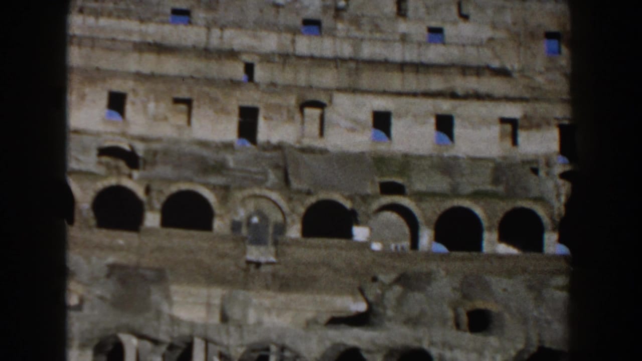 1959 8mm view inside the Roman Colosseum showing weathered stone walls, arched openings, and dark vertical film framing.