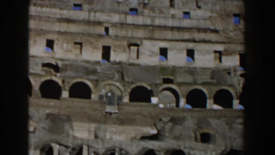 1959 8mm view inside the Roman Colosseum showing weathered stone walls, arched openings, and dark vertical film framing.