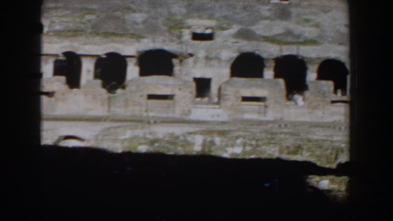 1959 Rome home-movie frame showing the Colosseum's weathered arches through a dark obstruction.