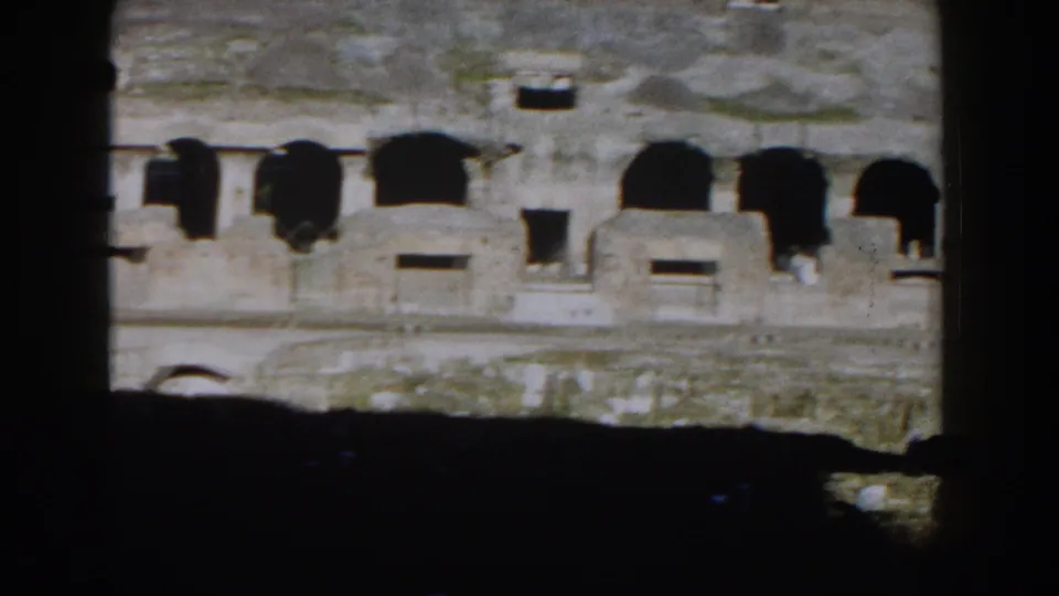 1959 Rome home-movie frame showing the Colosseum's weathered arches through a dark obstruction.