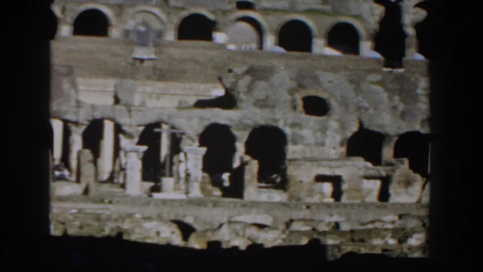 1959 8mm view from inside the Roman Colosseum, with layered stone arches and dark foreground framing.