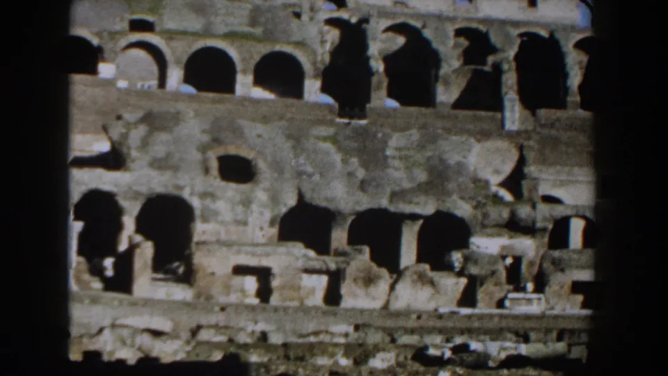 Rome Colosseum interior wall in 1959 8mm footage, partly divided by a dark vertical foreground element.